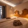 Cozy bedroom with two single beds and wooden decorations, warmly lit.