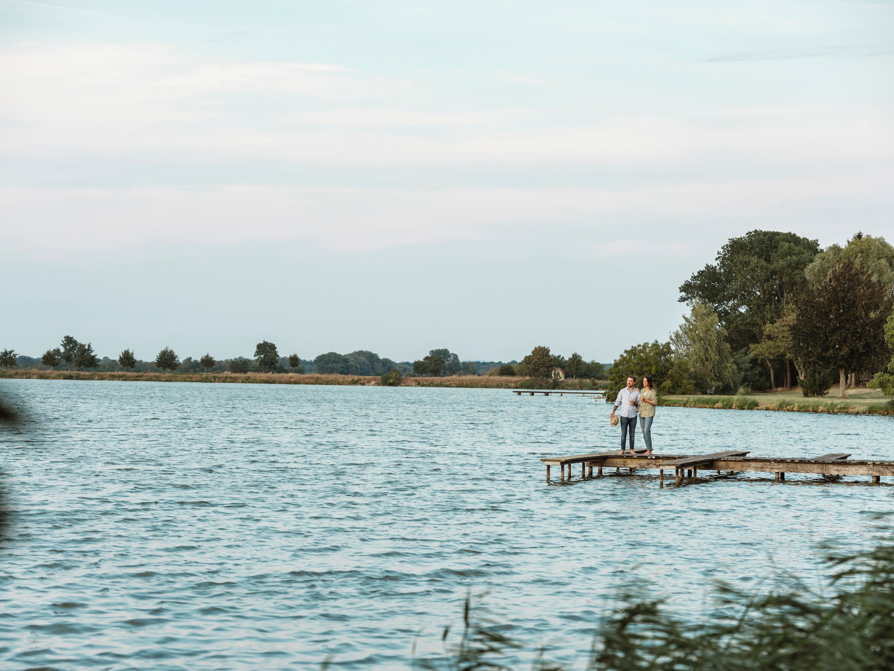 Two people stand on a footbridge at the landscaped pond in Bernhardsthal.