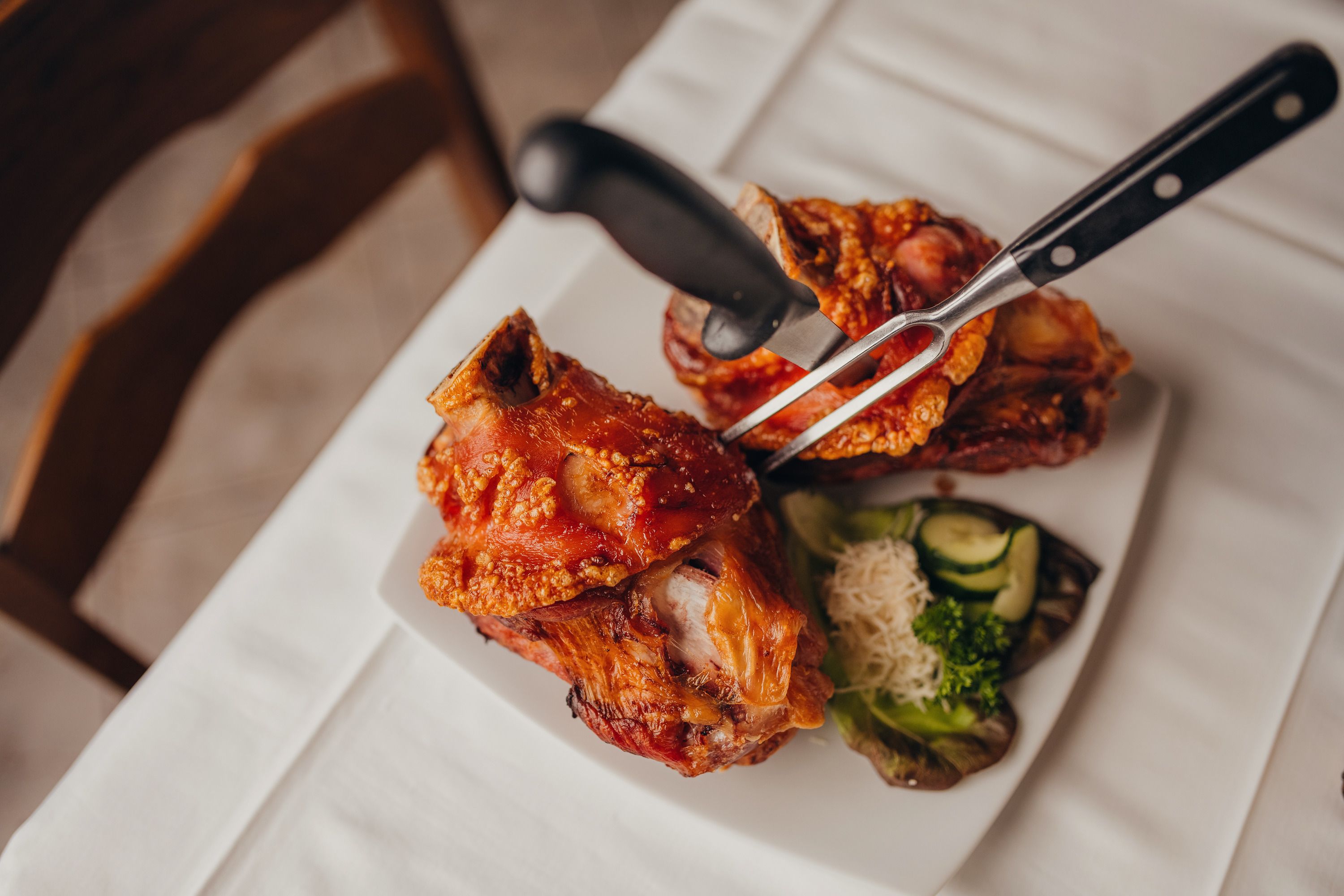 Two pork knuckles on a plate with side dishes.