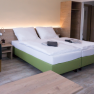 Modern furnished hotel room with double bed, bedside table, armchair and closet.