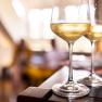 Two glasses of white wine on a table, blurred background.