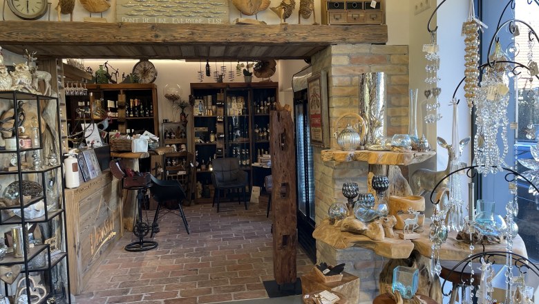 Interior view of a decoration store with wooden shelves, glassware and decorative items.