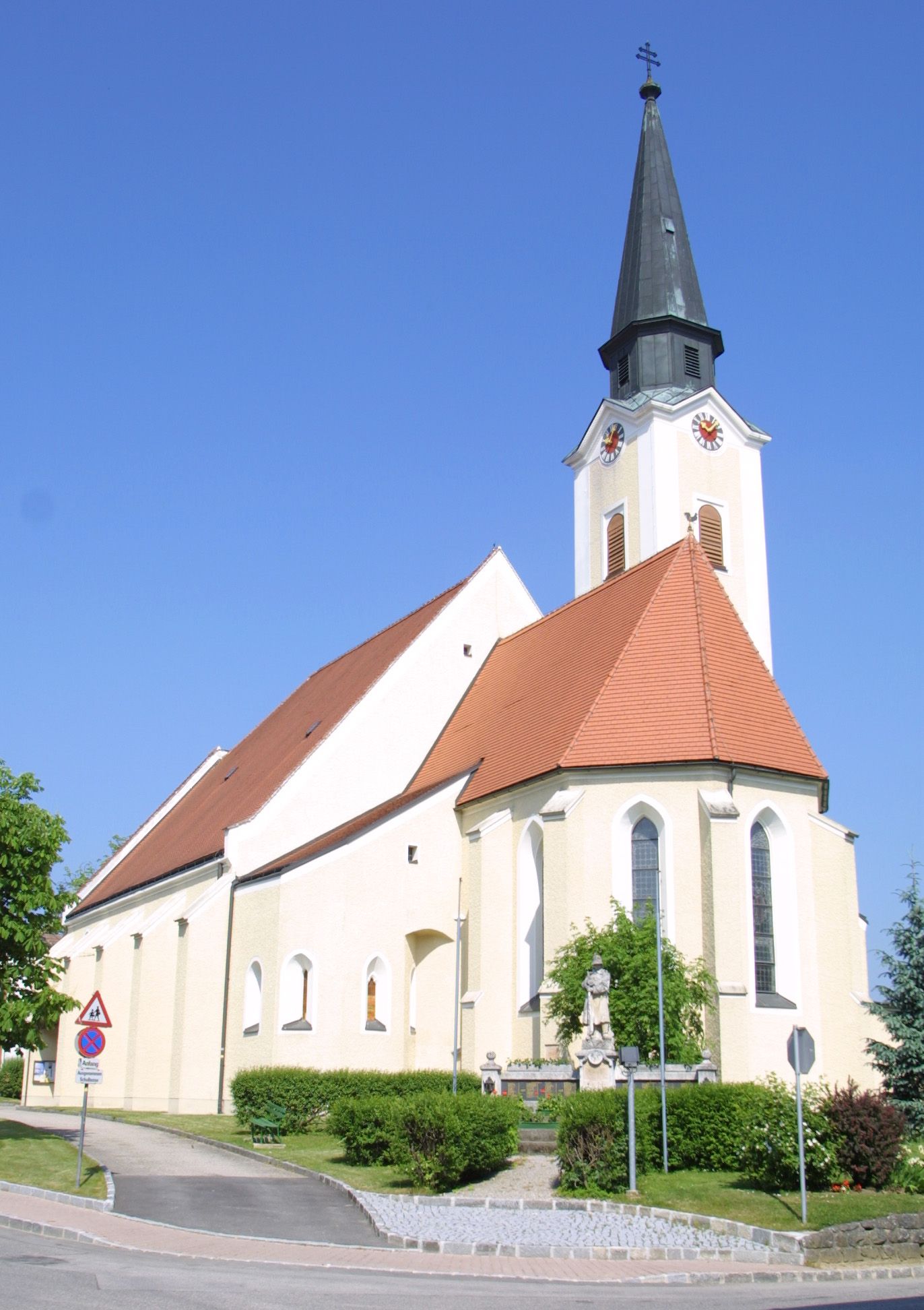 Church in Hürm with pointed tower and red roof against a blue sky.
