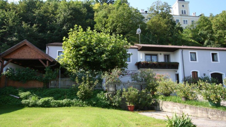 Exterior view of a house with garden and trees in the background.