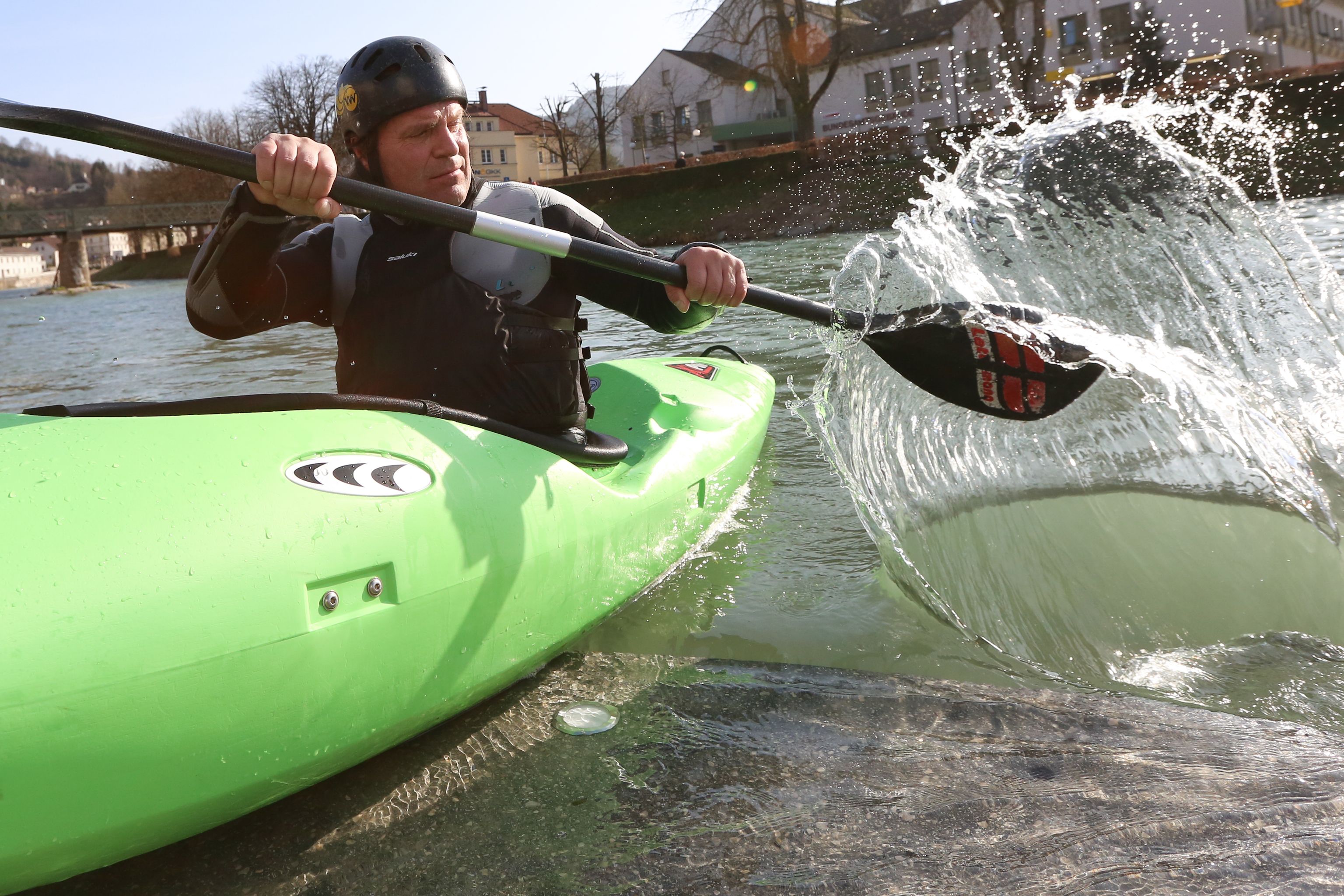 Person in green kayak paddling on a river.