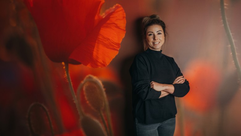 Woman standing in front of a wall with a poppy motif.