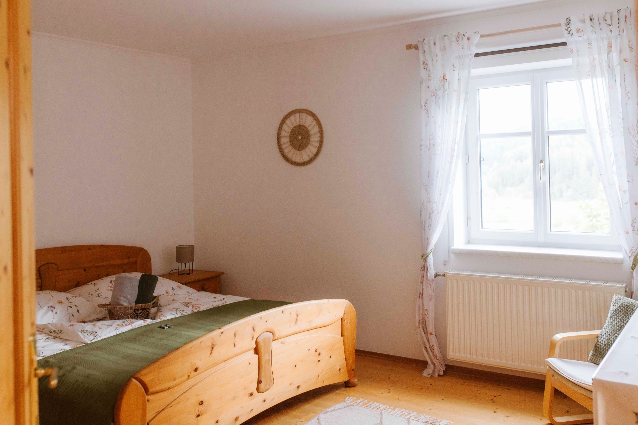 Cozy double room with wooden furniture and window with curtains.