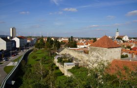 Town view of Bruck an der Leitha with town wall, church and wind turbines in the background.