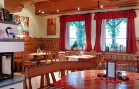 Cozy interior of a traditional Austrian wine tavern with wooden furniture and red curtains.