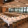 A large, modern seminar room with U-shaped tables, wooden chairs and large windows.