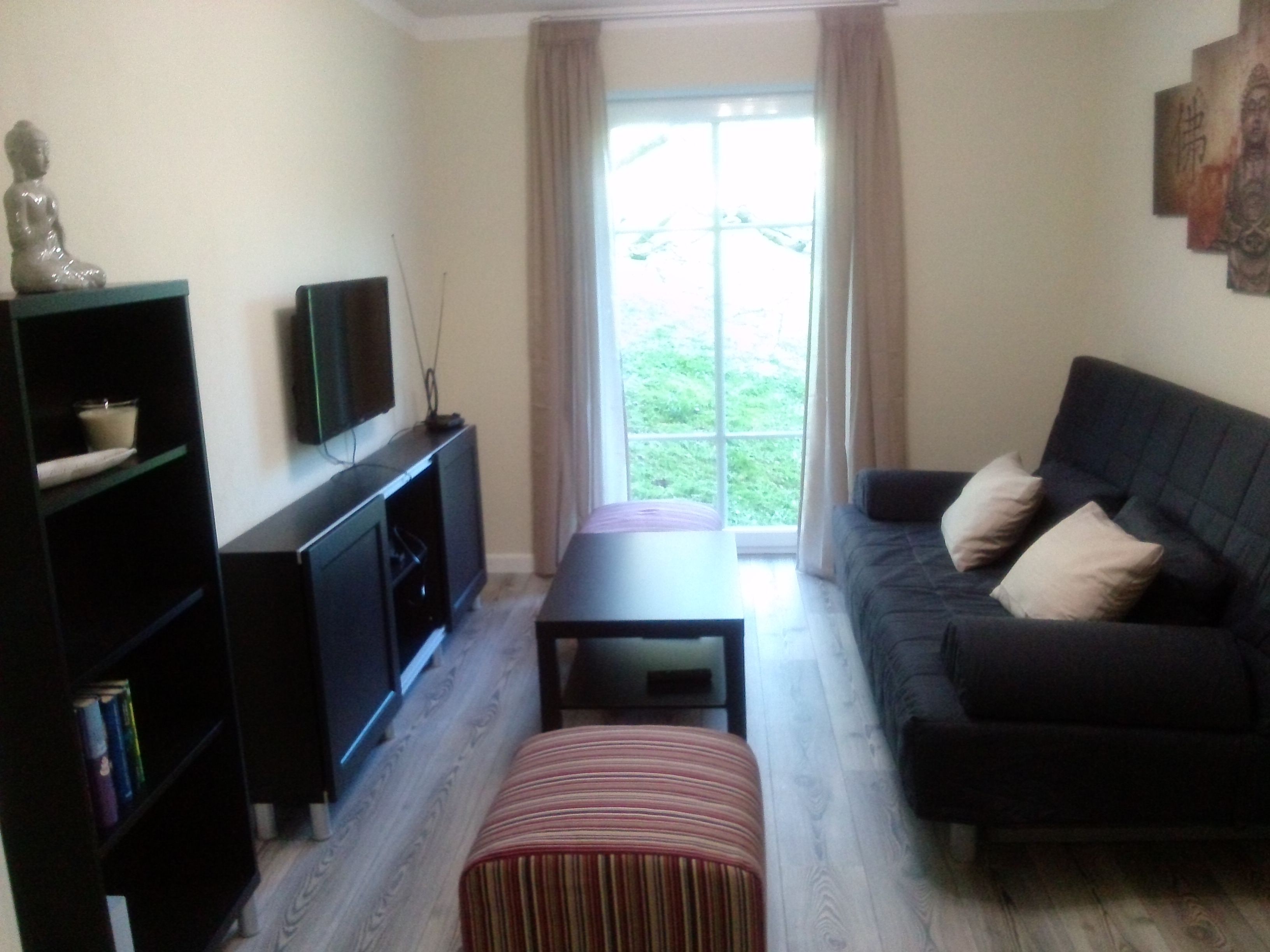Modern living room with sofa, coffee table, TV and bookshelf.