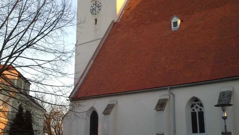 Church with red roof and clock tower in Kapelln at sunset.