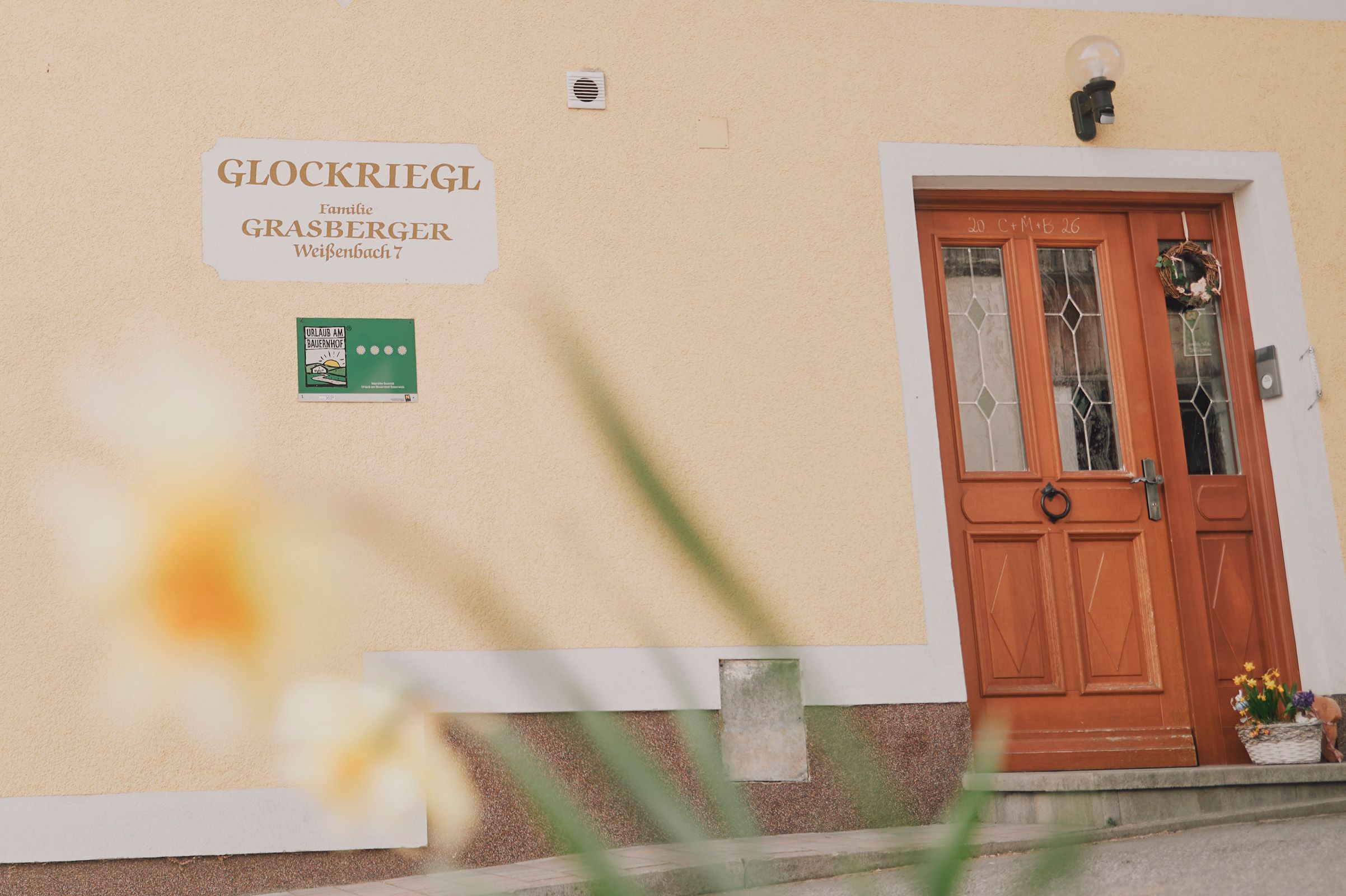 Entrance to a house with wooden door and "Glockriegl" sign on the wall.