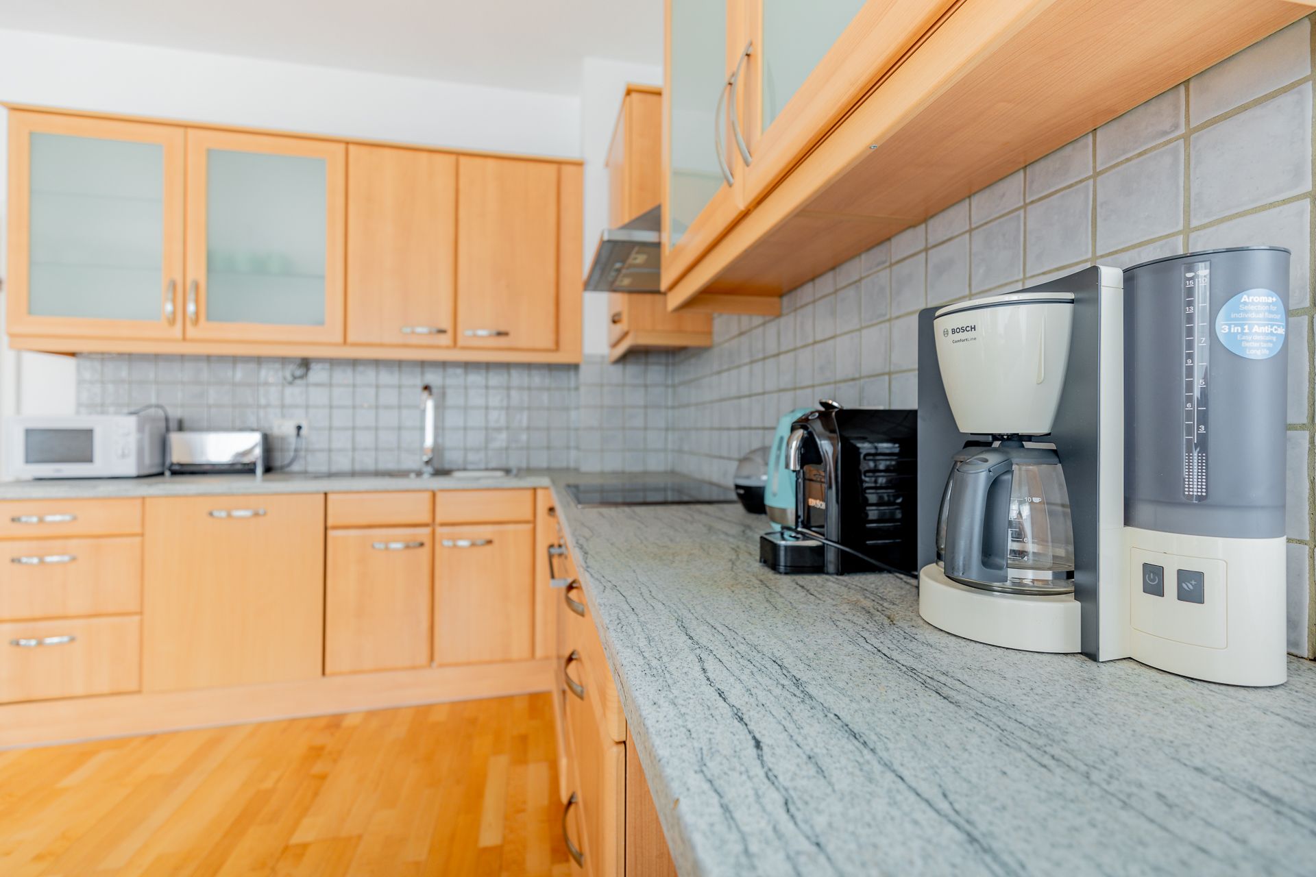Modern kitchen with wooden cupboards, coffee machine and toaster on the worktop.