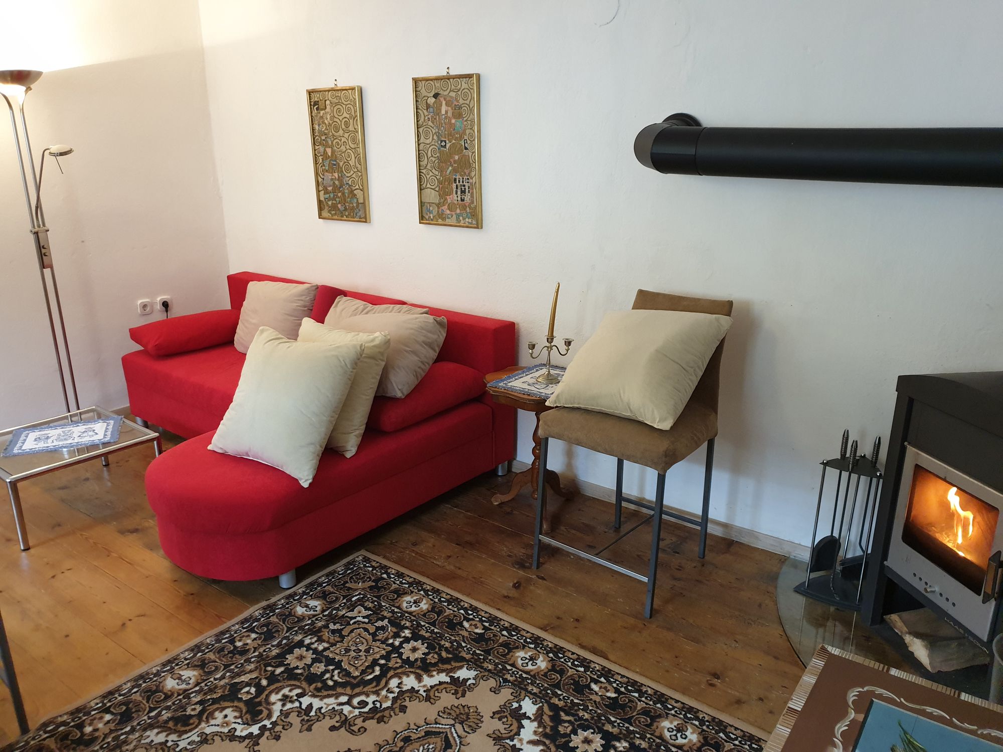Cozy living room corner with red sofa, fireplace and carpet.