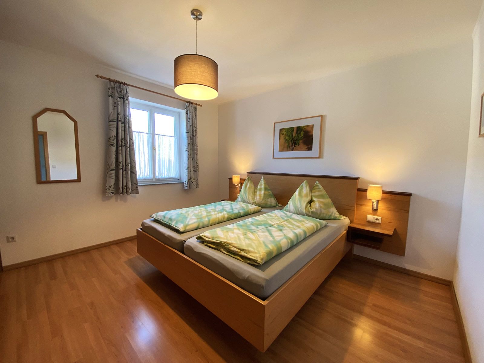 Bedroom with double bed, wooden floor, bedside tables and lamp.