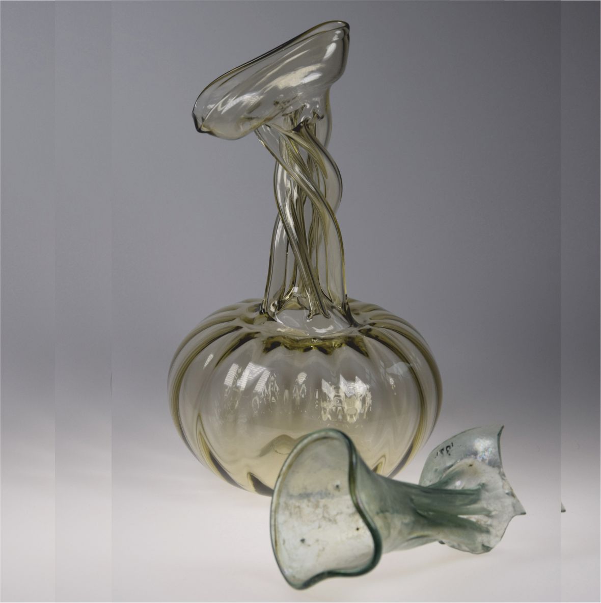 Glass object with twisted shapes on a gray background.