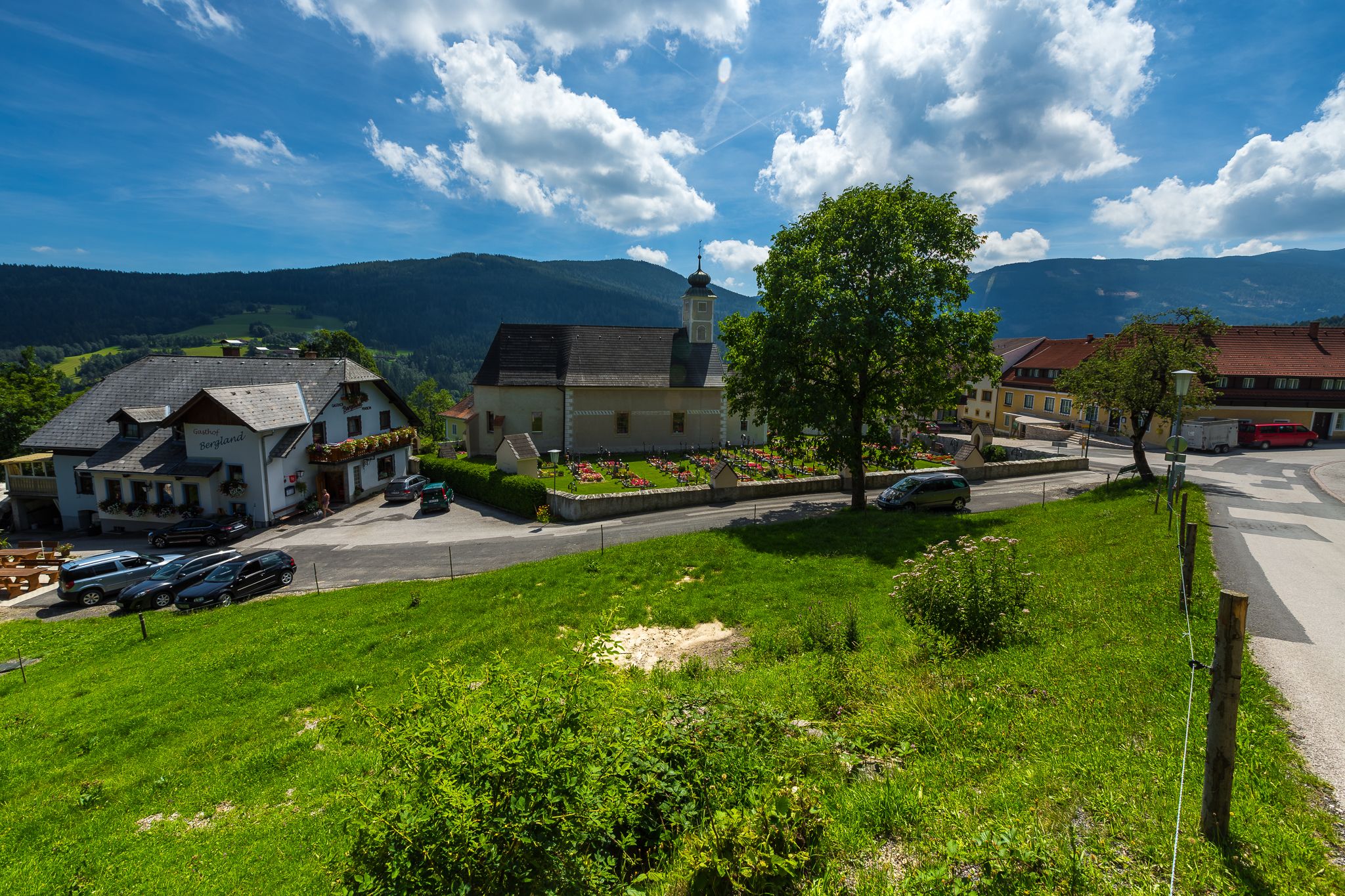Rural scene with church, inn and green meadow in Aspangberg-St. Peter.