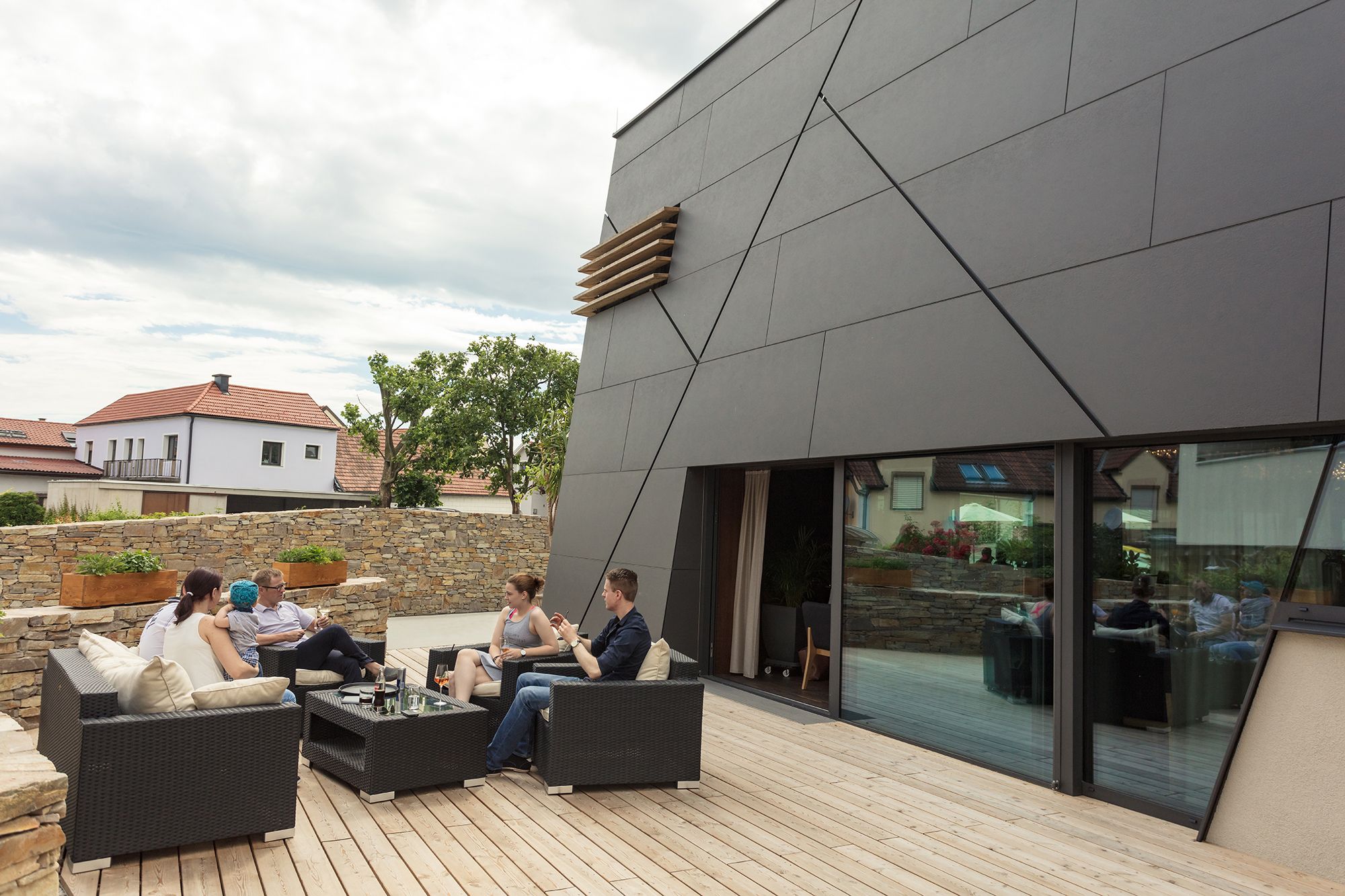 People sitting on a terrace in front of a modern building.