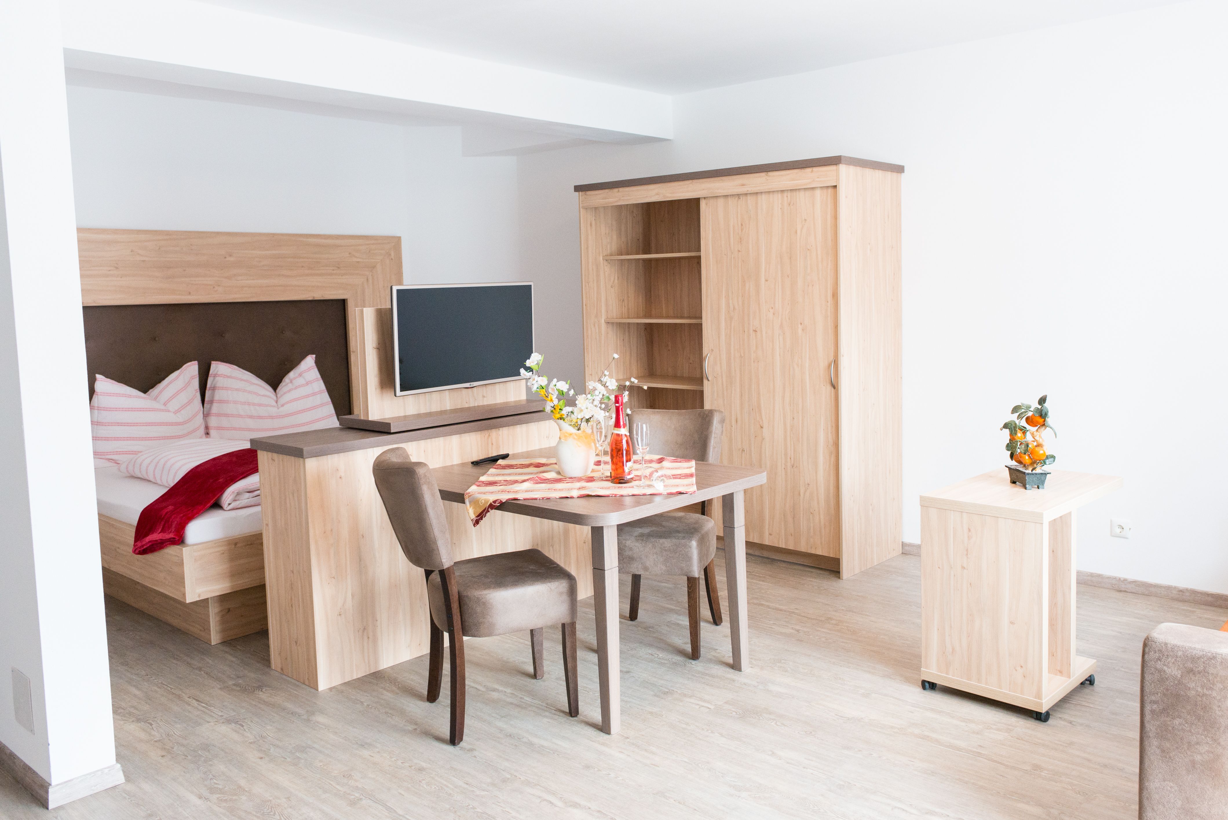 Modern apartment with wooden furniture, bed, table and TV.