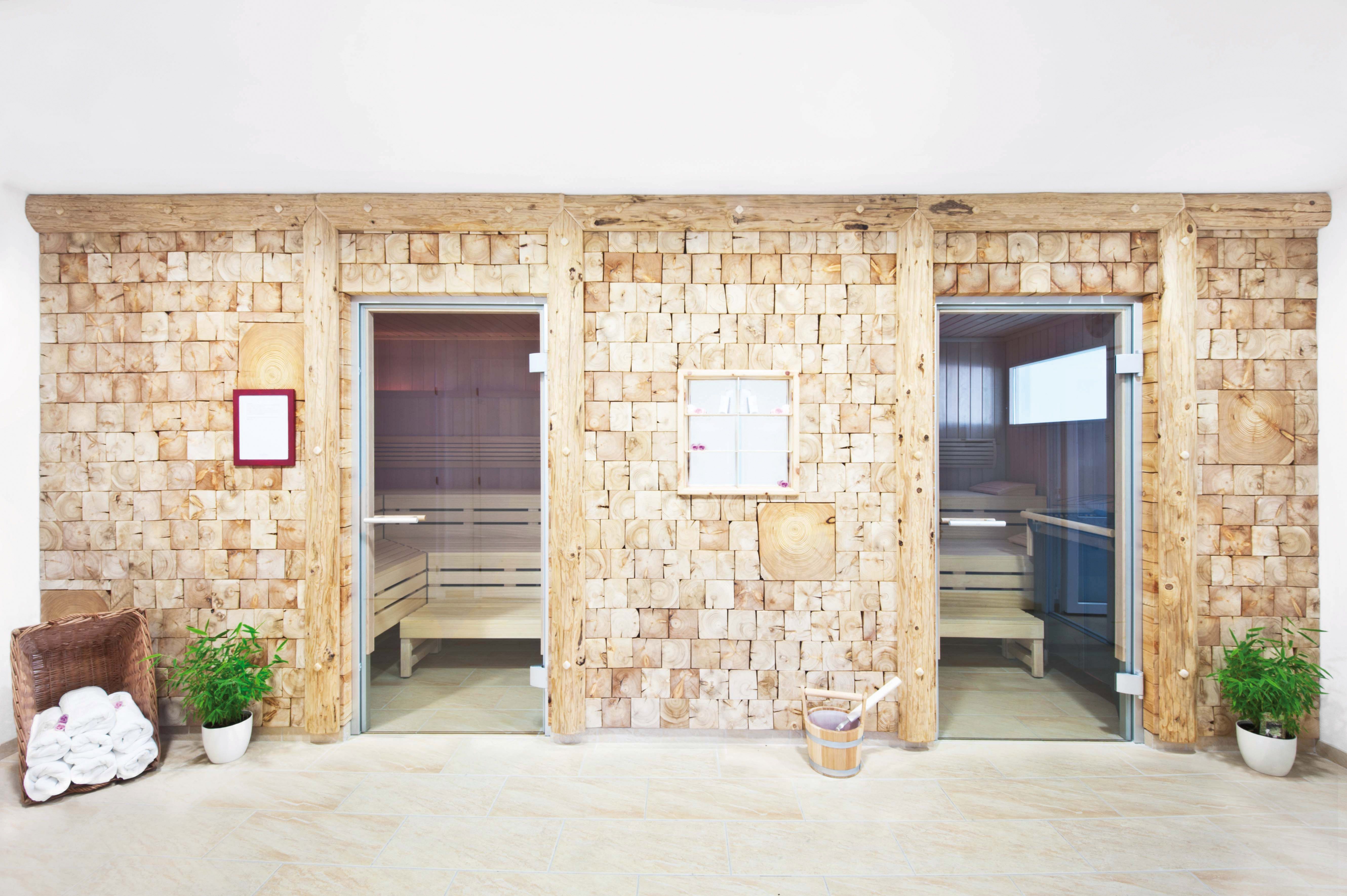 Two sauna cabins with wooden walls and glass doors in a wellness area.