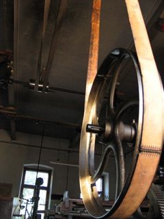 Large gear wheel with belt in an old factory building.