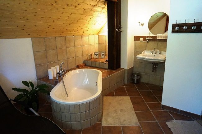 Rustic bathroom with bathtub, washbasin and wooden ceiling.