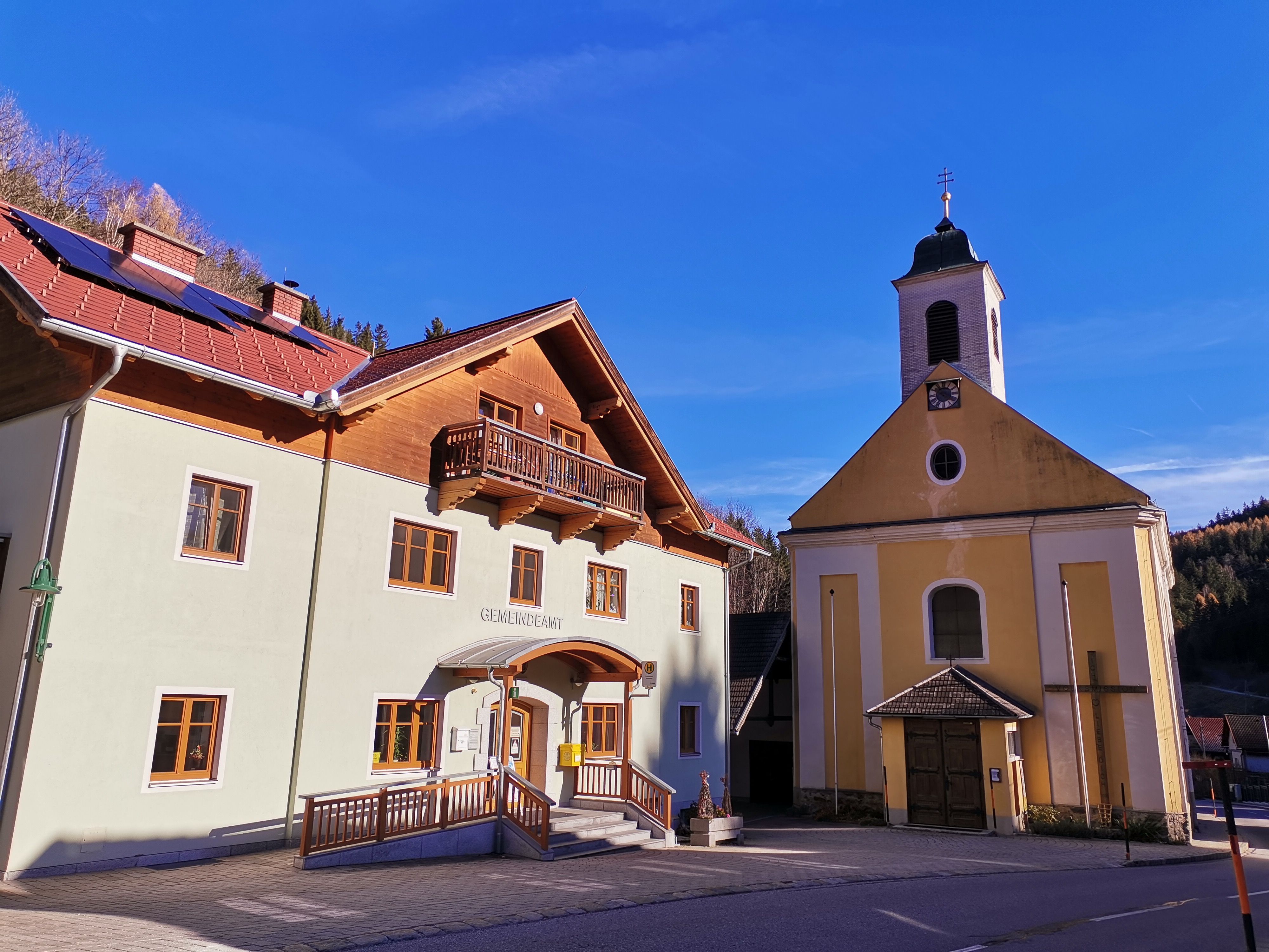 Municipal office and church in Trattenbach in sunny weather.