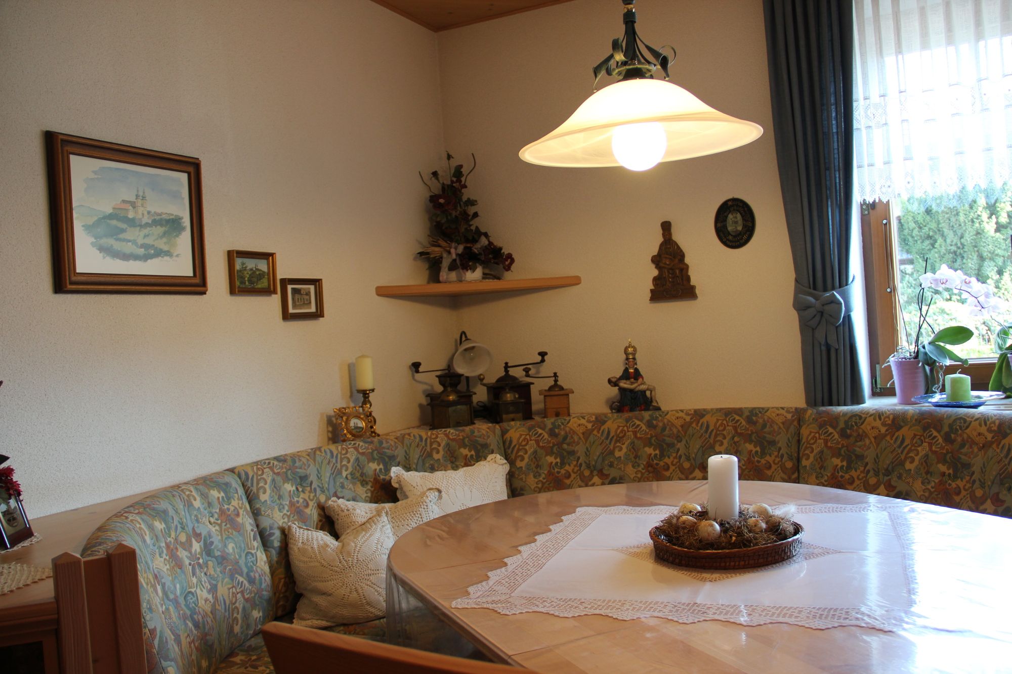 Cozy breakfast room with corner bench, table, candle and decorations on the wall.