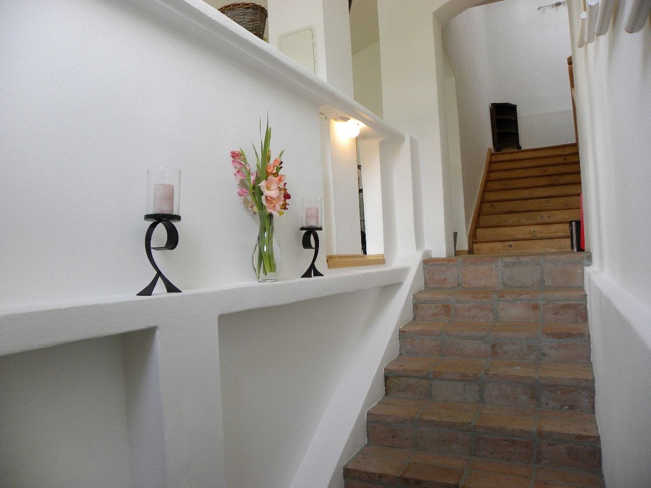 Interior view of a staircase with candlesticks and flowers on a ledge.
