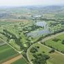 Aerial view of a golf course with lakes and surrounding fields.