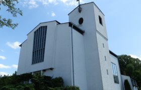 White church with tower and cross against a blue sky.