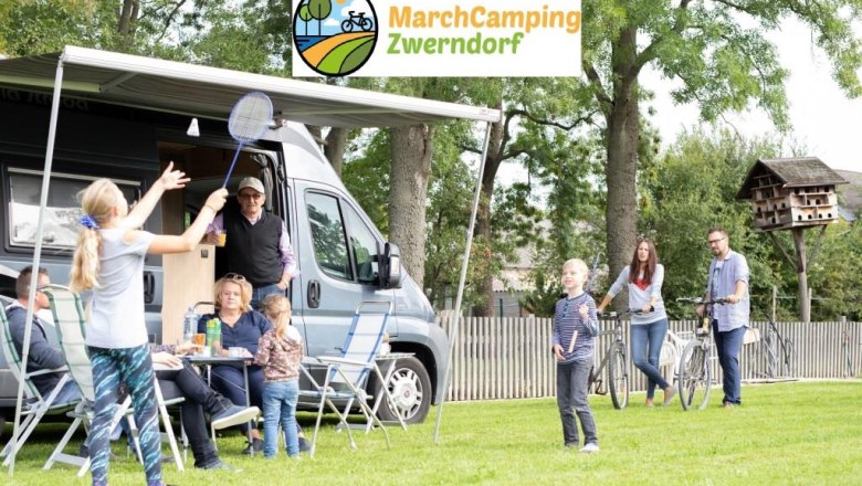 Family camping with motorhome and playing badminton on a meadow.