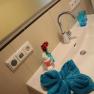 Washbasin with blue towel, soap dispenser and vase with flowers.
