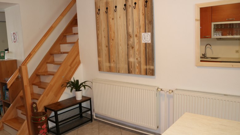 Interior with wooden staircase, checkroom, plant and kitchen window.