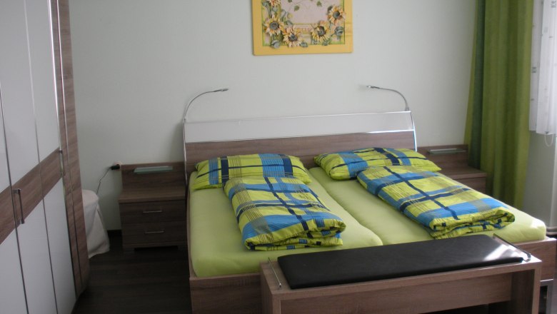 Guest room with double bed, colorful bedding and mural.
