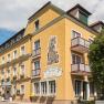Yellow hotel building with balconies and plants, blue sky in the background.