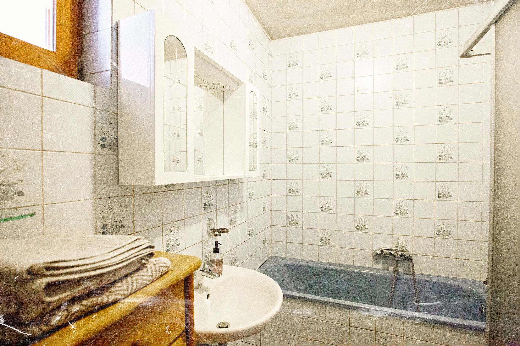 A bathroom with blue tiles, a bathtub, a sink, and a mirror.