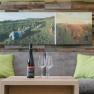 Living room with gray sofa, green cushions, wooden table, wine bottle and glasses, mural with vineyard.