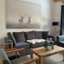 Living room with gray sofas, wooden table and deer picture on the wall.
