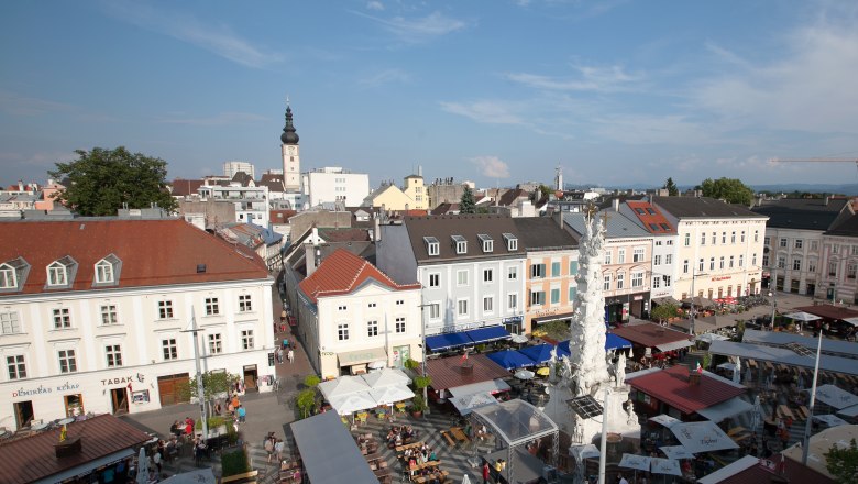 Aerial view of a busy square in St. Pölten with market stalls and a tower in the background.