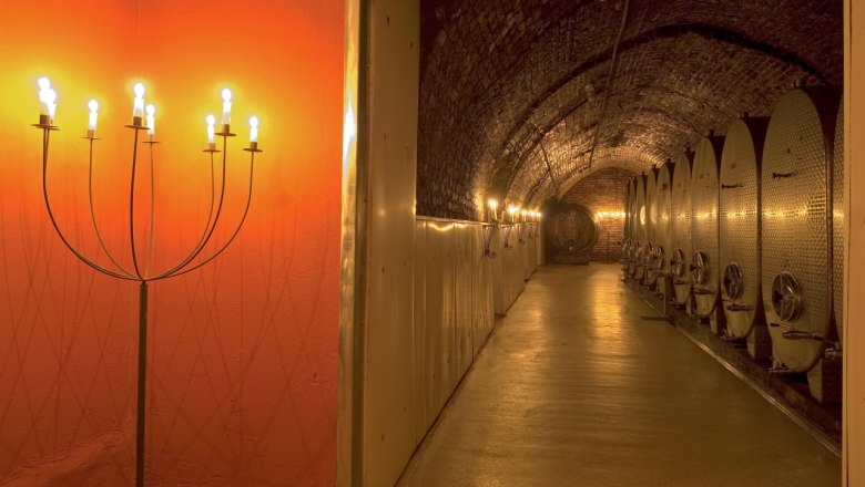 Wine cellar with illuminated metal tanks and candlesticks.