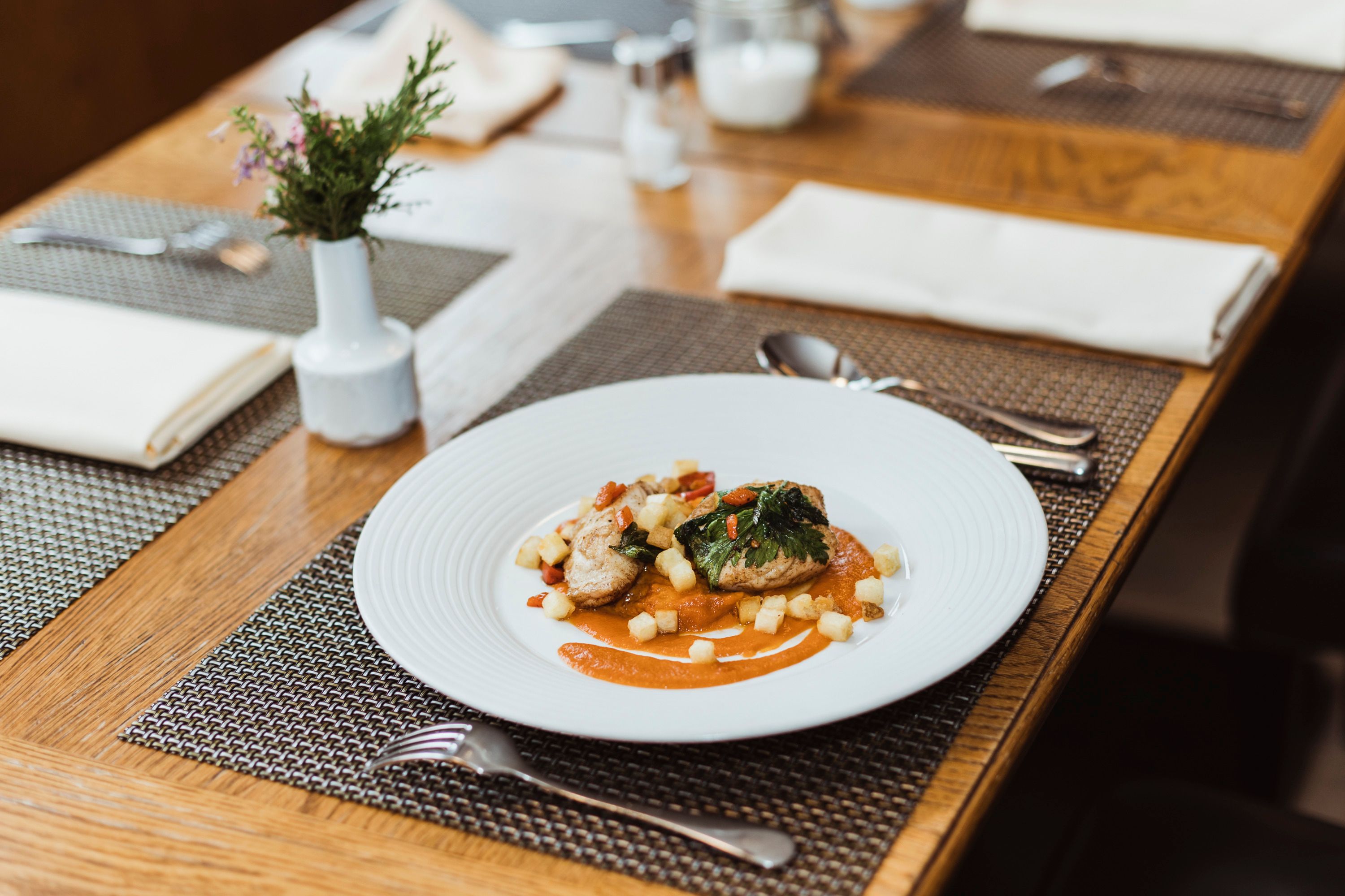 Elegant dish on a white plate, decoratively arranged on a wooden table.