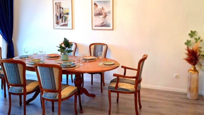 Dining room with oval wooden table, six chairs, two murals and decorations.
