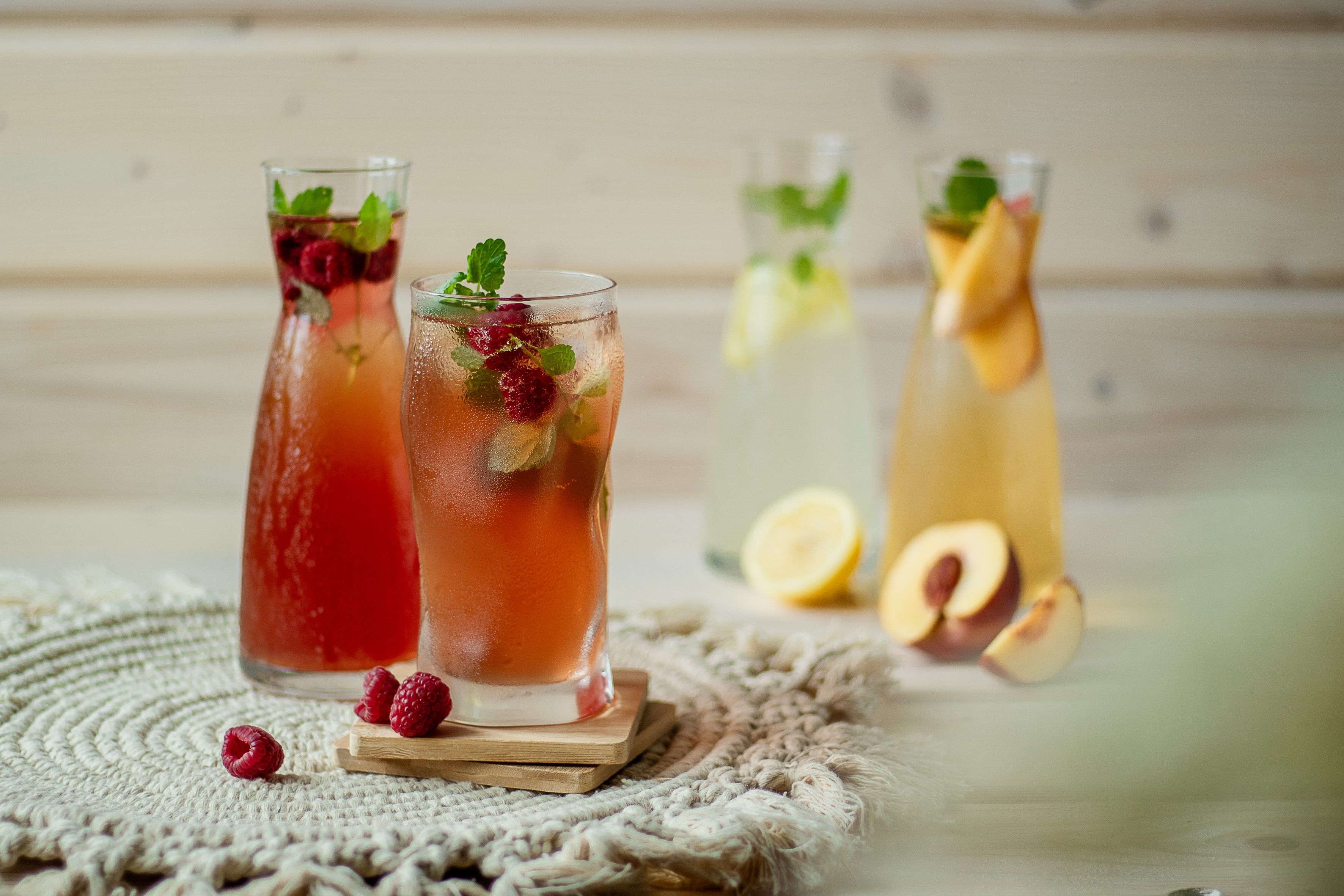 Various glasses of lemonade, decorated with fruit and mint, on a table.