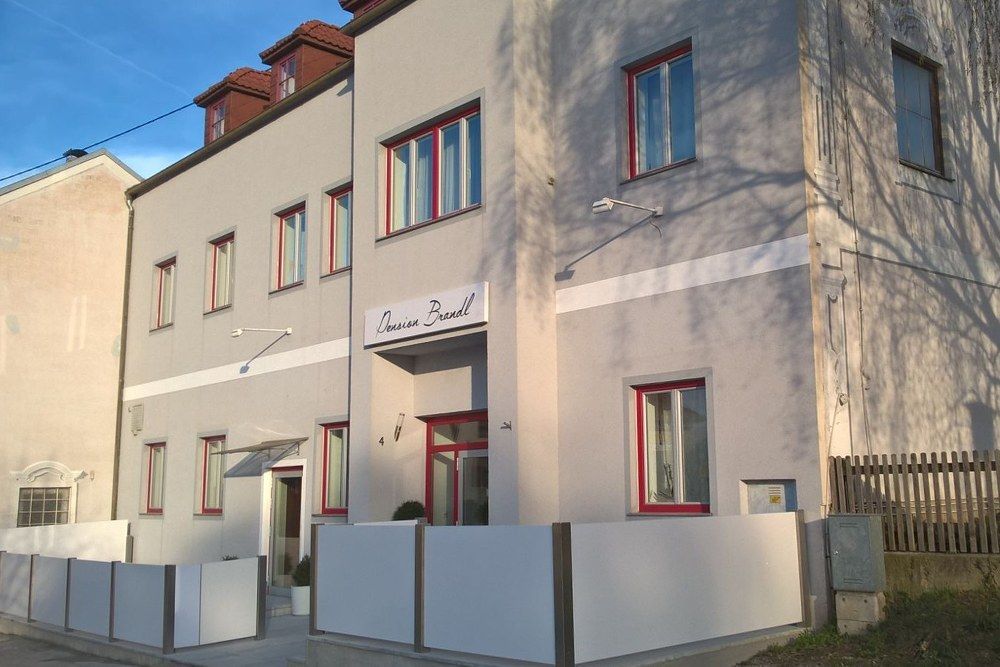 Exterior view of Pension Brandl with gray facade and red window frames.