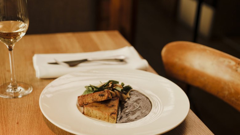 Elegant dish with wine on a wooden table in a stylish restaurant.