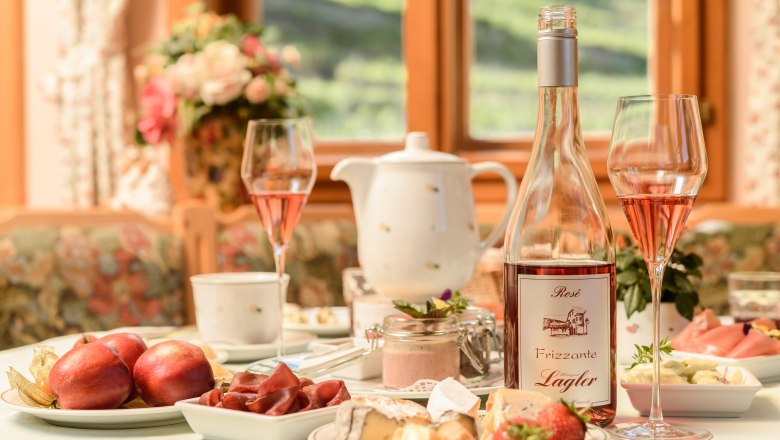 Breakfast at the Weinberghof, © Rita Newman Breakfast table with fruit and cheese and a bottle of Frizzante