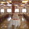A large, elegantly decorated hall with long, laid tables and seating for over 200 people.