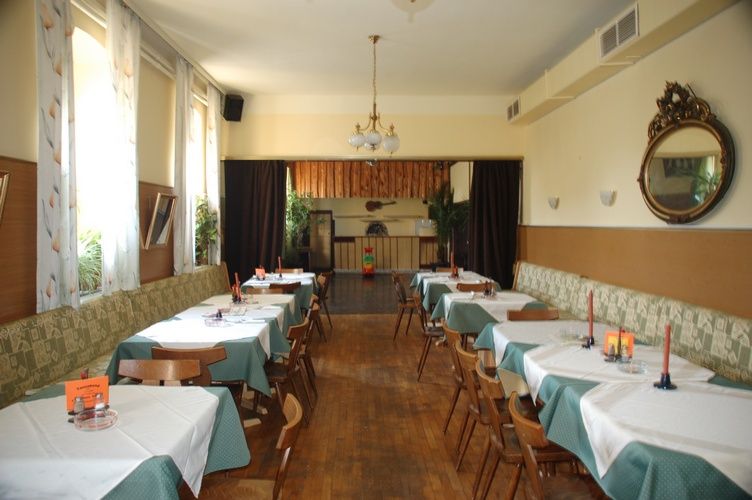 A traditional inn with wooden floors, laid tables and a chandelier.
